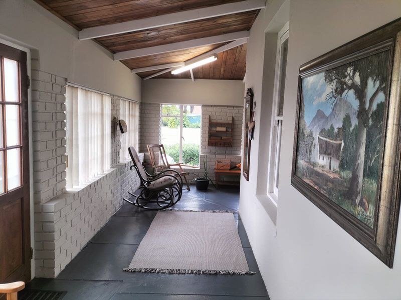 Enclosed patio area featuring painted brick walls, exposed timber ceiling beams, and painted concrete flooring, offering a versatile space for relaxation.