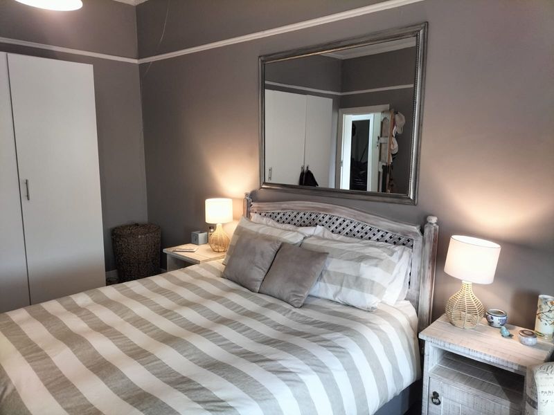 A cozy bedroom featuring built-in wardrobes, decorative picture rails, and coving, finished in a neutral grey tone.