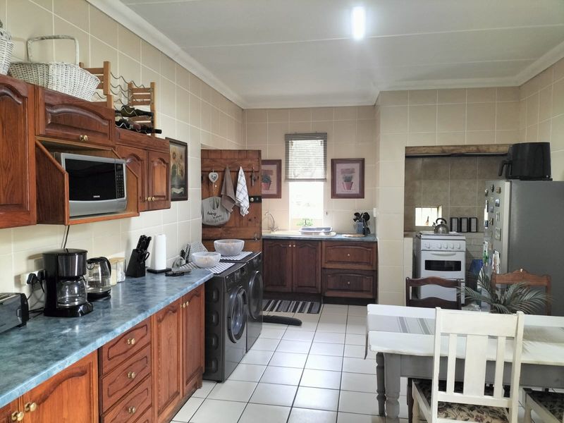 A functional kitchen featuring traditional wooden cabinetry, tiled splashbacks, tiled flooring, and integrated appliance spaces, offering a classic layout with potential for modernization.
