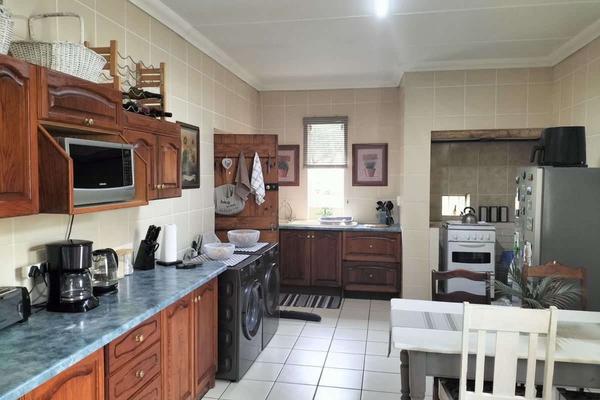 A functional kitchen featuring traditional wooden cabinetry, tiled splashbacks, tiled flooring, and integrated appliance spaces, offering a classic layout with potential for modernization.