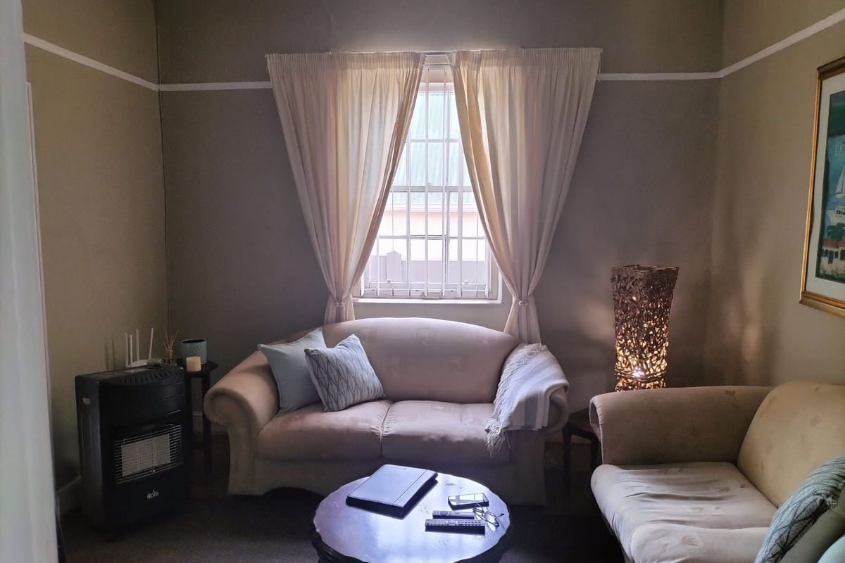 A cozy living room featuring a central window with security bars, classic picture rails, and coving, providing a comfortable and traditional living space.