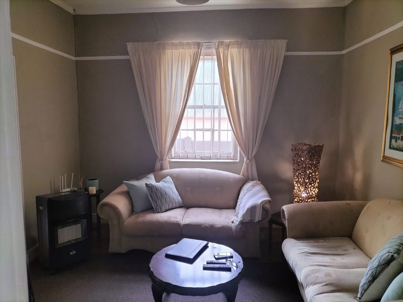 A cozy living room featuring a central window with security bars, classic picture rails, and coving, providing a comfortable and traditional living space.