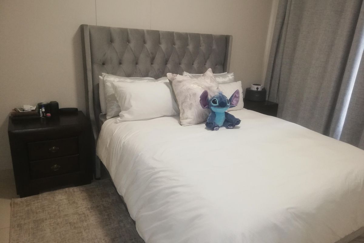 A cozy bedroom featuring a tufted grey headboard and neutral wall tones, providing a comfortable and inviting sleeping space.