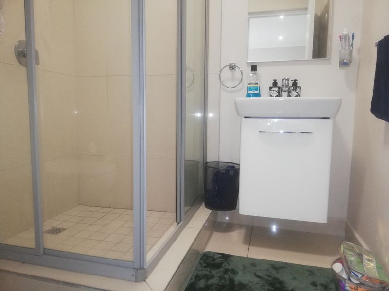 A compact modern bathroom featuring a glass-enclosed shower and a wall-mounted vanity unit with a basin.