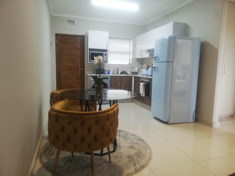 Compact open-plan kitchen and dining area featuring modern cabinetry, tiled floors, and integrated appliances, creating a functional and efficient living space.