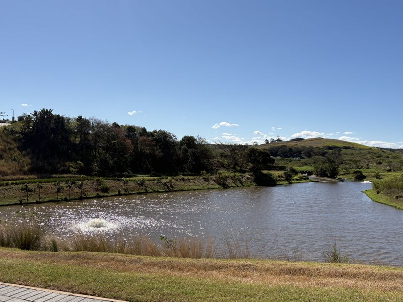 A scenic view of a tranquil lake surrounded by natural vegetation and rolling hills, offering a peaceful landscape setting.