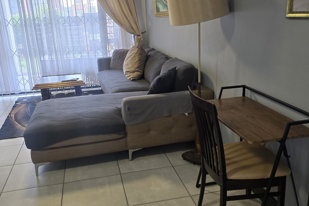 A living room area featuring tiled flooring and a sliding glass door with an integrated security gate, providing access to the exterior.