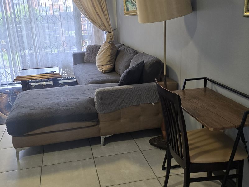 A living room area featuring tiled flooring and a sliding glass door with an integrated security gate, providing access to the exterior.