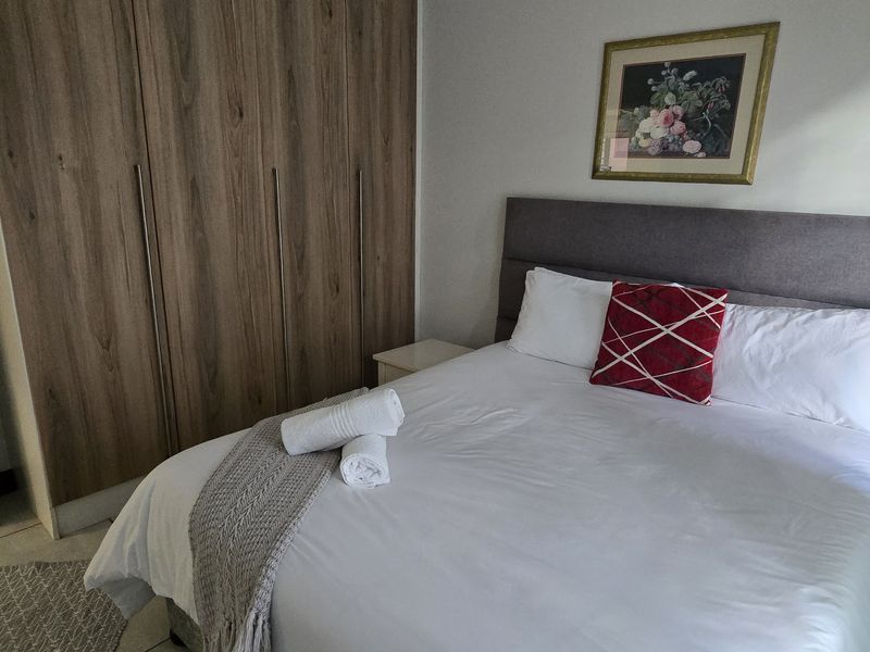 A well-maintained bedroom featuring built-in wooden cupboards and neutral tiled flooring, providing a clean and functional living space.