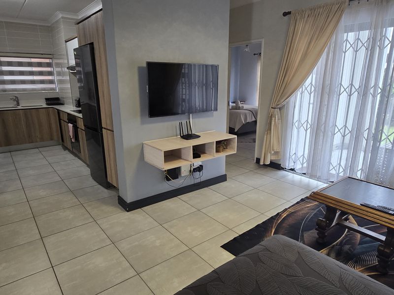 Open-plan living area featuring a modern kitchen with wood-finish cabinetry, tiled flooring, and direct access to an outdoor patio through sliding glass doors.