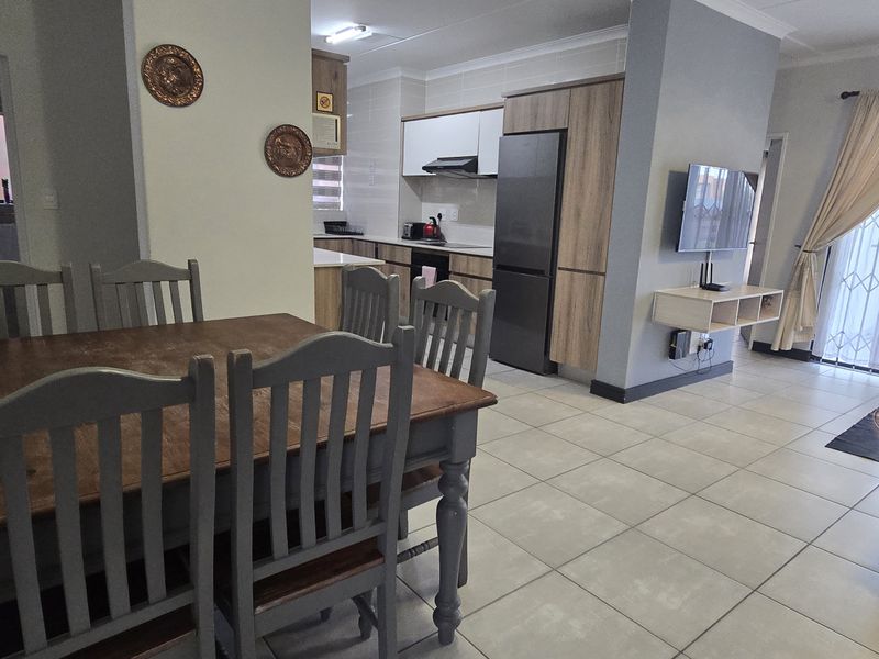 Open-plan living and dining area featuring tiled floors, modern kitchen cabinetry, and a sliding door leading to an outdoor space.