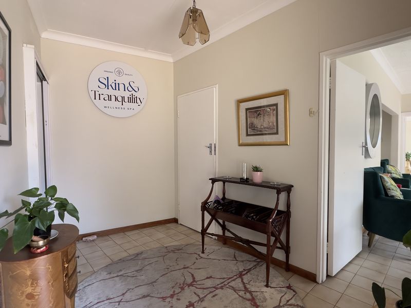 A bright entrance foyer featuring tiled flooring and access to adjacent living spaces, currently utilized as a commercial reception area.