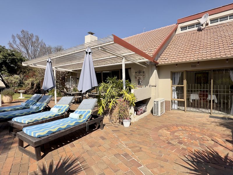 A paved outdoor patio area featuring a covered section, sliding door access to the home, and an integrated air conditioning unit.