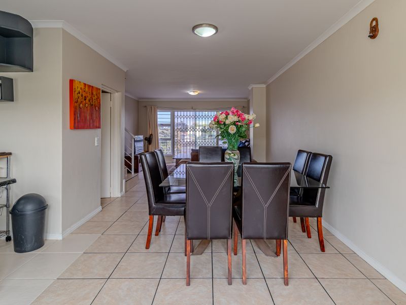 Open-plan living and dining area featuring neutral wall tones, ceramic tiled flooring, and direct access to an outdoor space through a sliding glass door.
