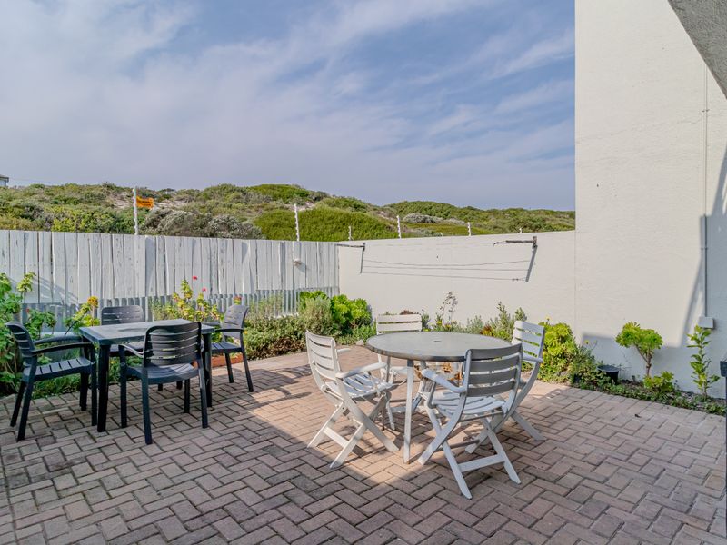 A paved outdoor patio area featuring a boundary wall and a wall-mounted washing line, offering a functional space for outdoor relaxation.