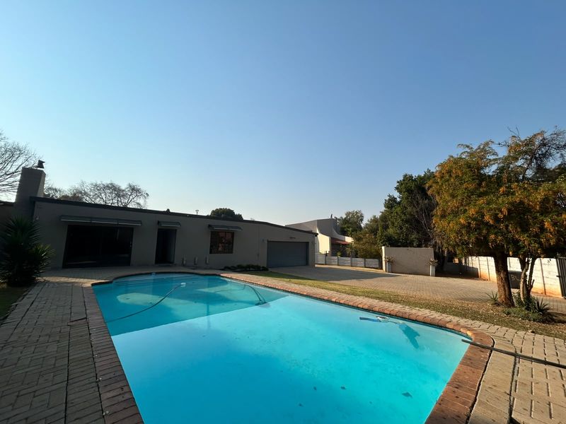 Spacious outdoor area featuring a large swimming pool, paved driveway, and direct access to the garage.