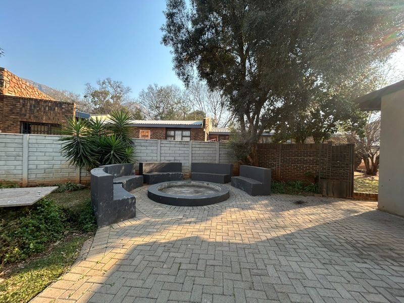 Outdoor patio area featuring a paved surface, built-in concrete fire pit, and integrated bench seating, enclosed by brick and precast boundary walls.