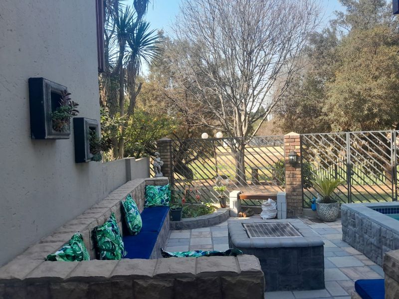 Outdoor patio area featuring a built-in stone bench, integrated fire pit, and brick accents, overlooking a garden space.