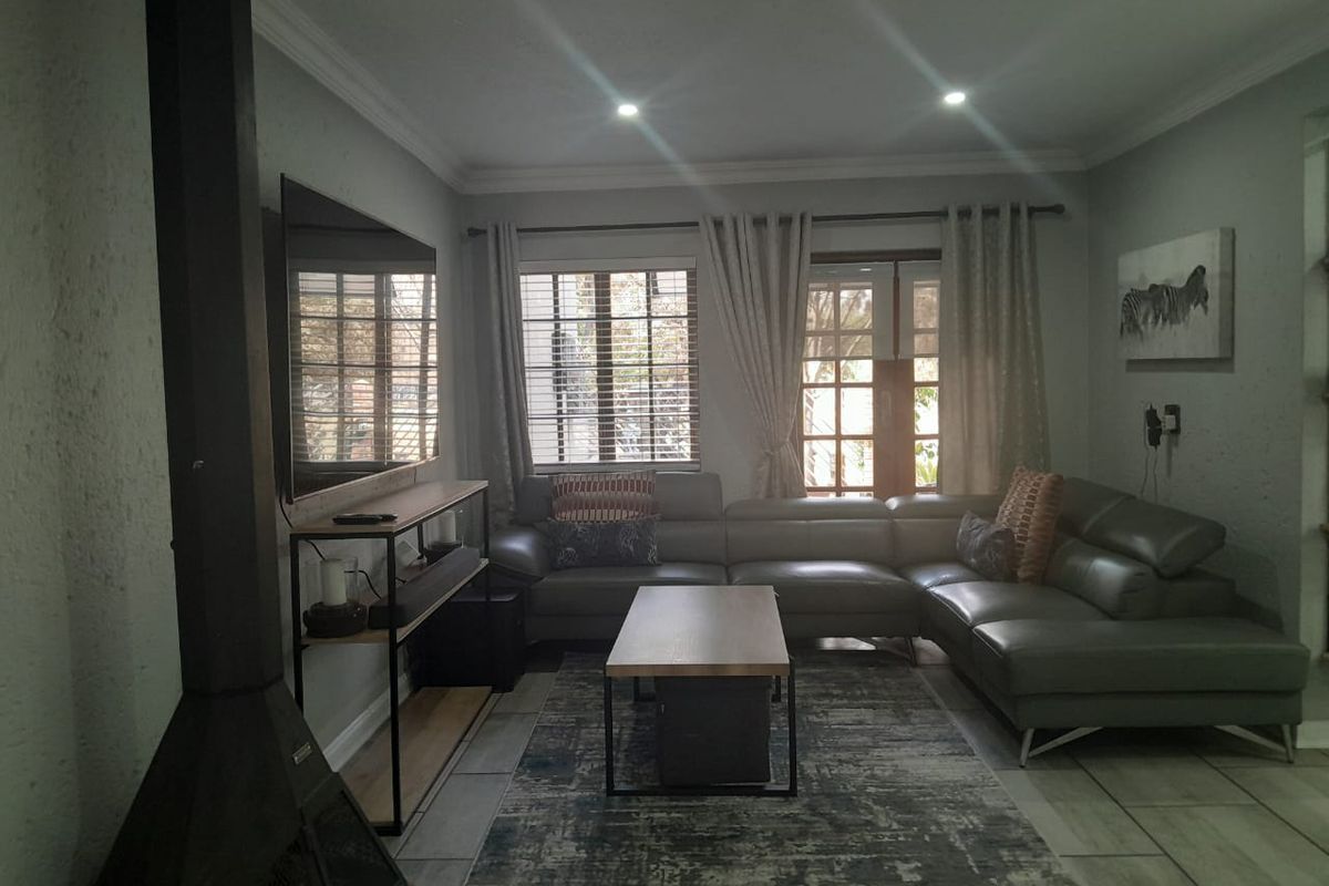 A comfortable living room featuring tiled flooring, a freestanding fireplace, and direct access to the outdoors through french doors.
