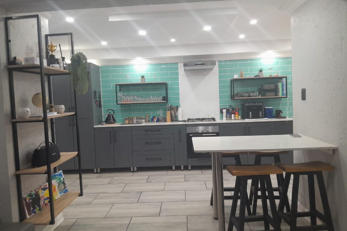 Modern kitchen featuring dark grey cabinetry, vibrant teal subway tile backsplash, gas hob, built-in oven, and integrated breakfast bar area with recessed lighting.