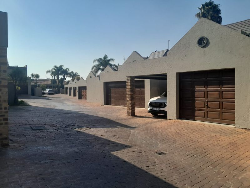 A view of the property's exterior featuring a brick-paved driveway and multiple garage doors along the residential facade.