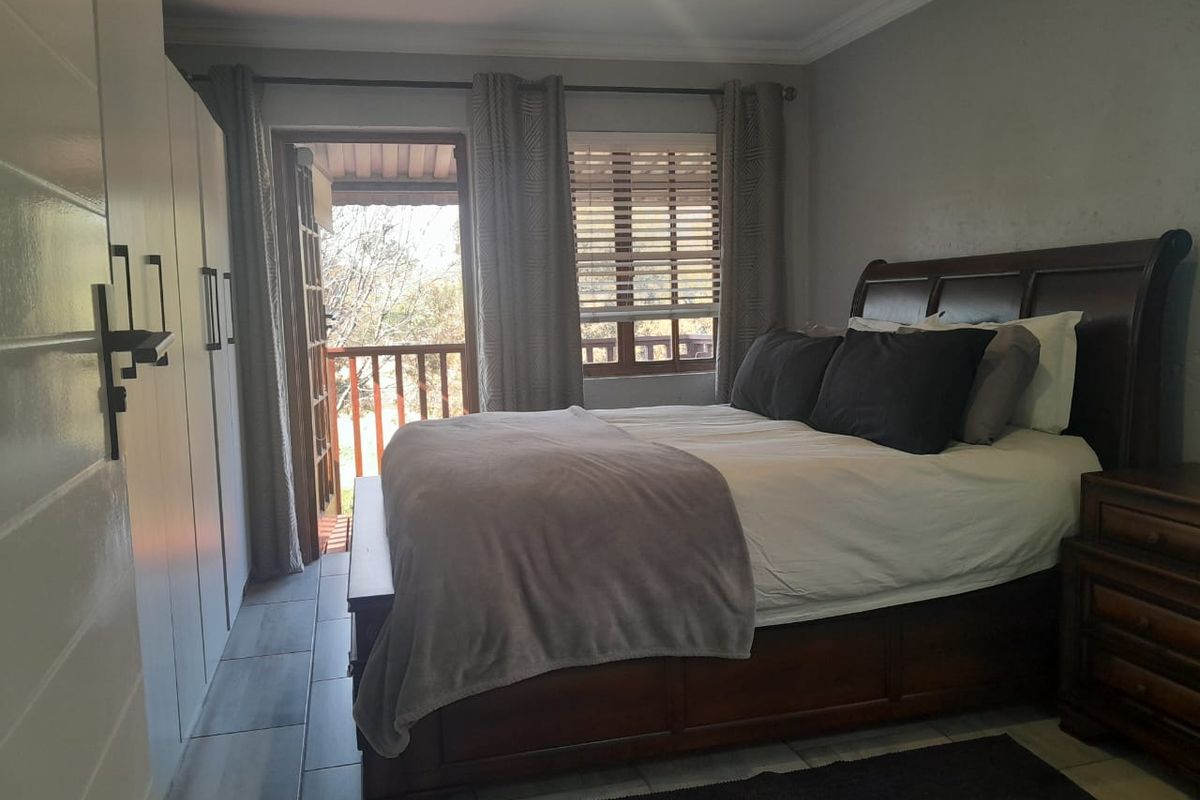 A bedroom featuring built-in cupboards, tiled flooring, and direct access to an outdoor balcony through a sliding door.