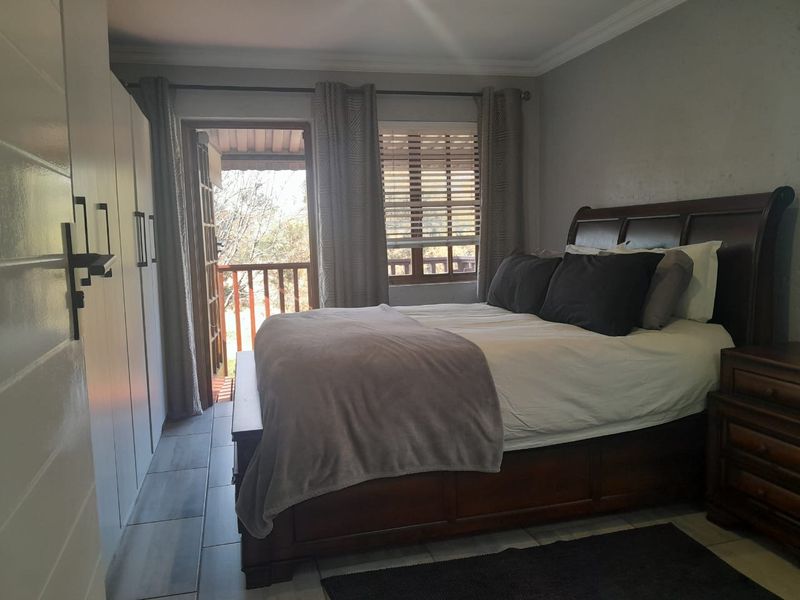 A bedroom featuring built-in cupboards, tiled flooring, and direct access to an outdoor balcony through a sliding door.