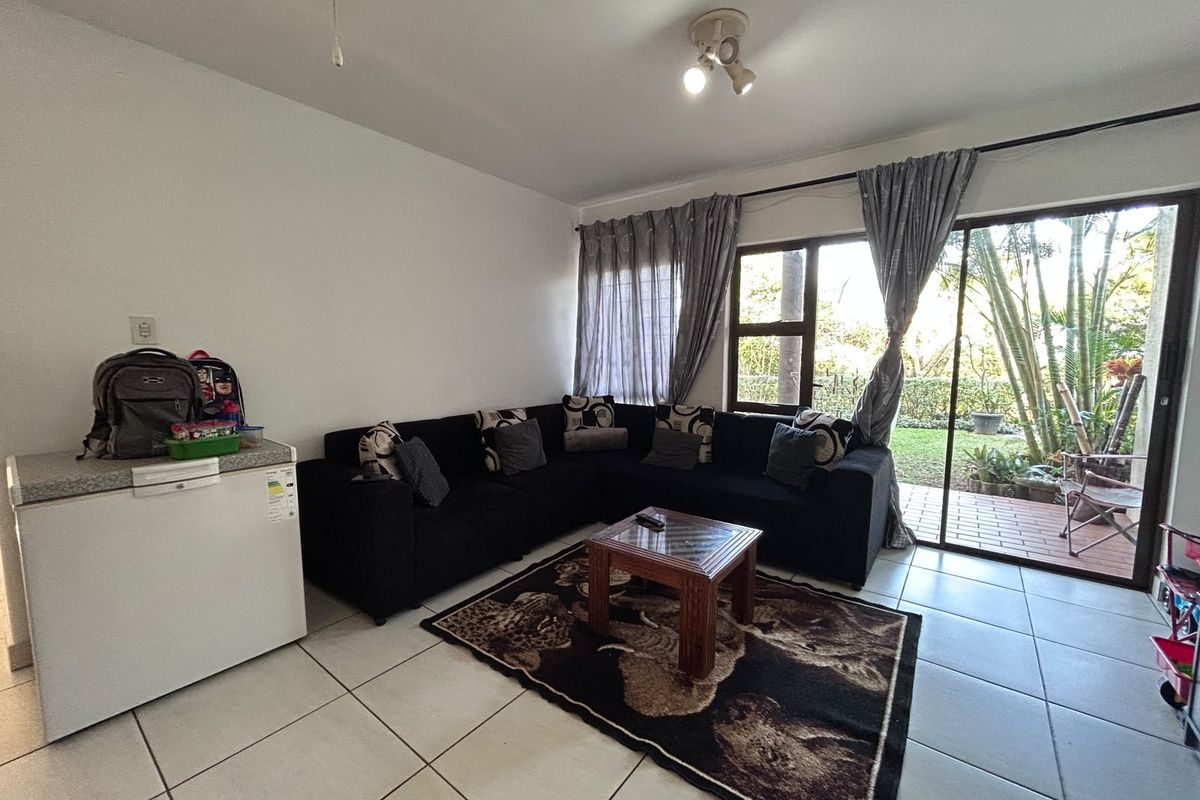 A living room featuring tiled flooring and a large sliding glass door providing access to an outdoor patio area.