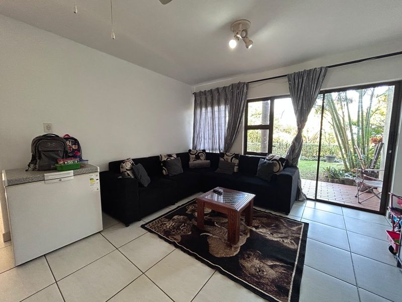 A living room featuring tiled flooring and a large sliding glass door providing access to an outdoor patio area.