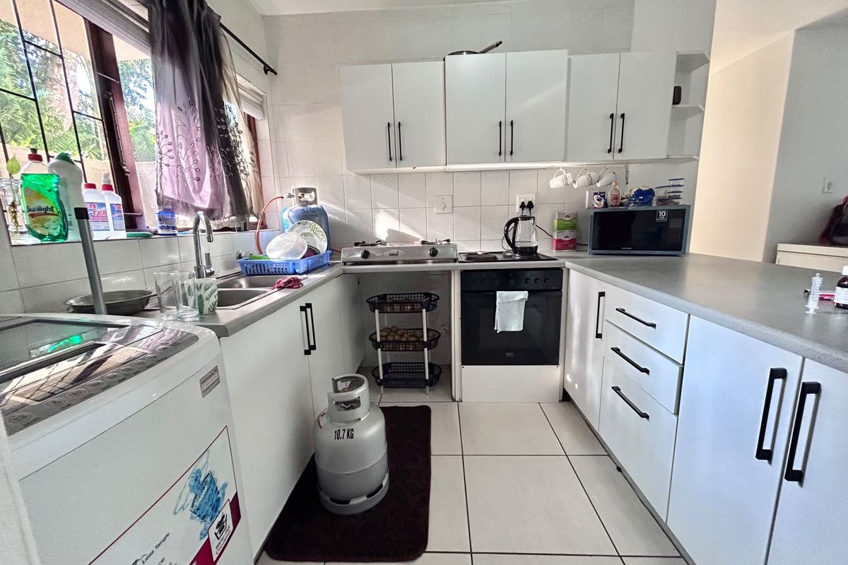 Functional kitchen featuring white cabinetry, laminate countertops, gas hob, built-in oven, and tiled flooring with a practical layout.
