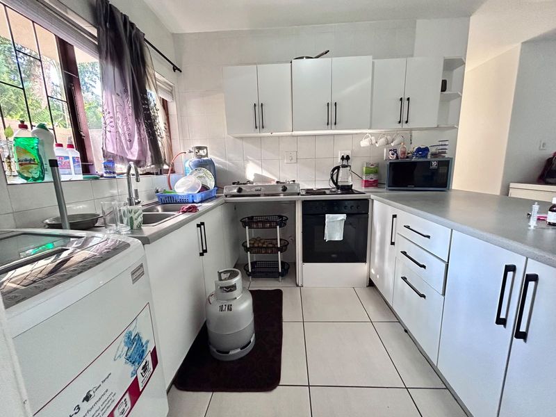 Functional kitchen featuring white cabinetry, laminate countertops, gas hob, built-in oven, and tiled flooring with a practical layout.