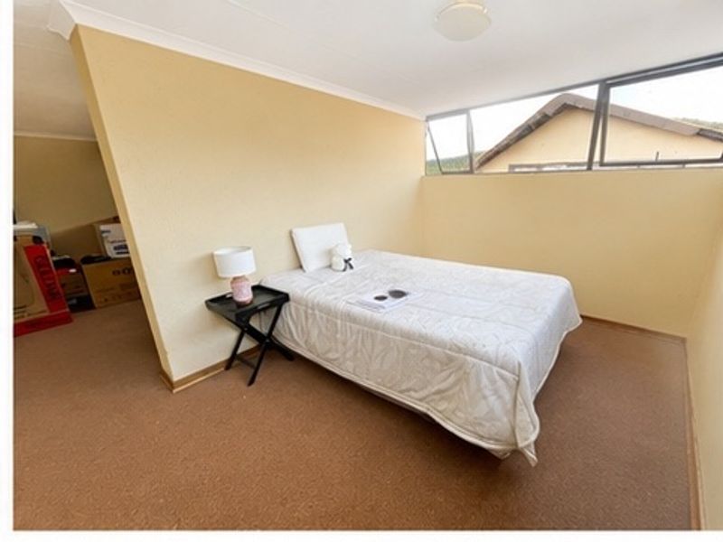 A simple bedroom featuring carpet flooring, coving, and top-hung windows, offering a functional space ready for modernization.