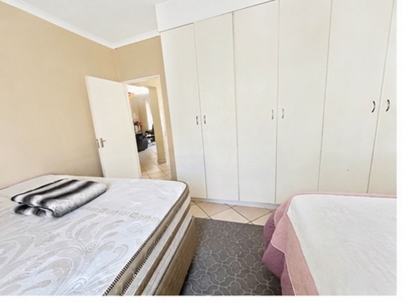 A bedroom featuring built-in cupboards, tiled flooring, and coved cornicing, with direct access to the hallway.