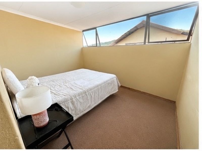 A simple bedroom featuring carpeted flooring and high-set clerestory windows providing natural light.