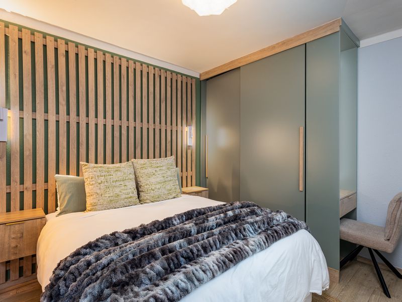 Modern bedroom featuring a timber slat feature wall, integrated wardrobe with vanity, and high-quality laminate flooring.