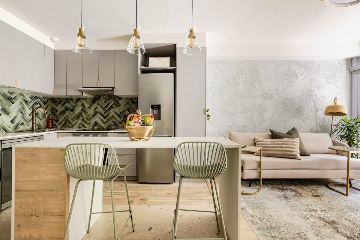 Modern open-plan living area featuring a contemporary kitchen with herringbone tile backsplash, sleek cabinetry, and a functional island, seamlessly connected to the living space.