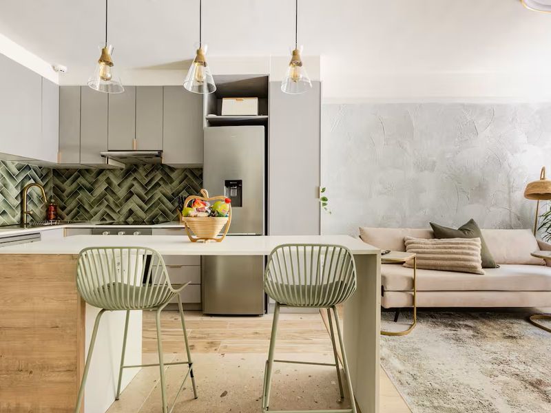 Modern open-plan living area featuring a contemporary kitchen with herringbone tile backsplash, sleek cabinetry, and a functional island, seamlessly connected to the living space.