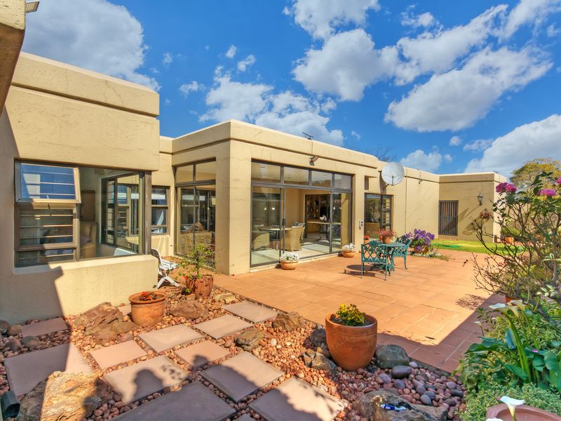 A well-maintained rear exterior view featuring a tiled patio area, large sliding glass doors, and established garden landscaping.