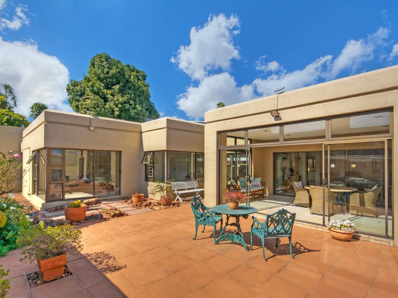 A spacious rear patio area featuring tiled flooring, large sliding glass doors providing indoor-outdoor flow, and well-maintained exterior walls.