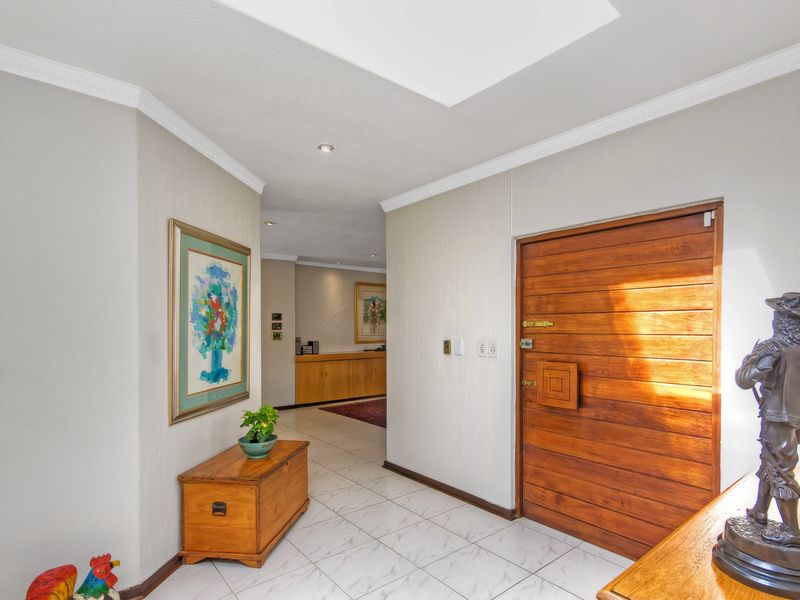 Welcoming entrance hall featuring a solid wooden front door, bright skylight, and neutral tiled flooring leading into the main living area.