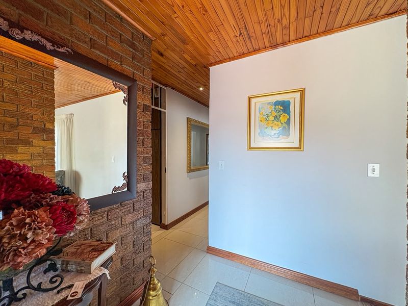 A well-maintained hallway featuring exposed brickwork, a warm timber tongue and groove ceiling, and neutral tiled flooring.