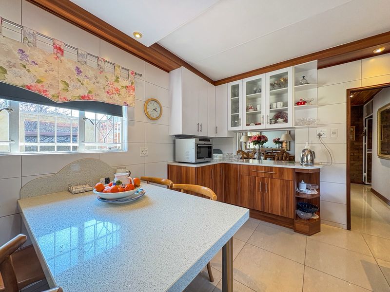 A functional kitchen featuring wood-grain and white cabinetry, tiled splashbacks, and a built-in breakfast nook with stone-look countertops.