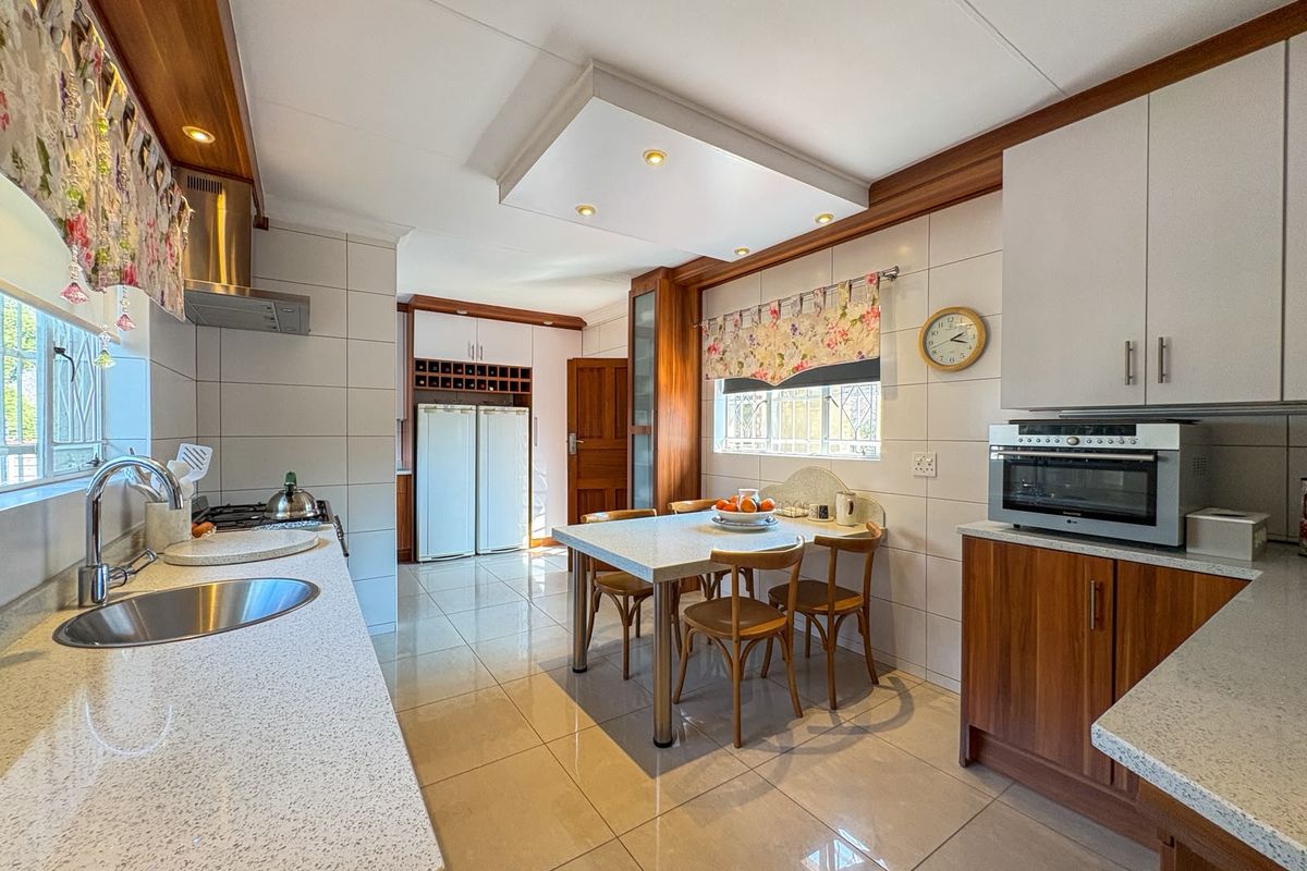 A well-maintained kitchen featuring stone countertops, built-in cabinetry, integrated oven, and tiled flooring, offering a functional and organized cooking and dining space.