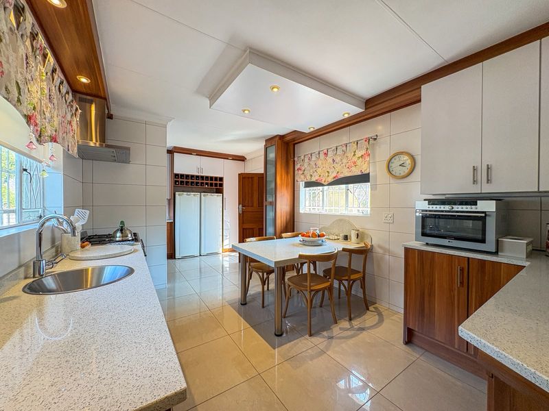A well-maintained kitchen featuring stone countertops, built-in cabinetry, integrated oven, and tiled flooring, offering a functional and organized cooking and dining space.