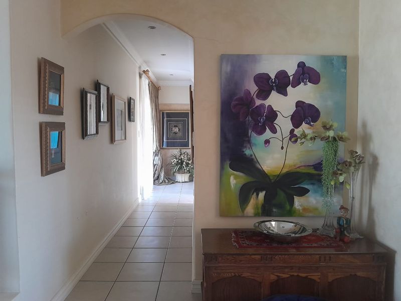 A bright and welcoming hallway featuring tiled flooring, an elegant arched entryway, and recessed downlighting, leading through to the main living areas.