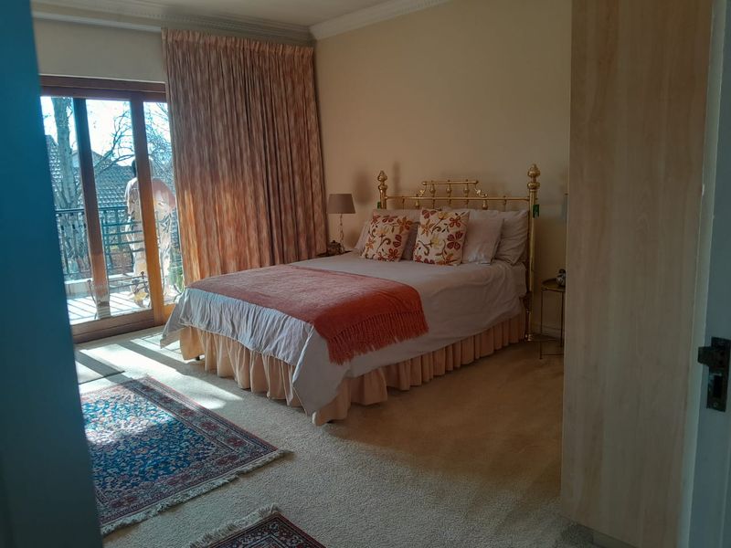A carpeted bedroom featuring a built-in wardrobe, cornice detailing, and a sliding glass door providing direct access to an outdoor balcony.