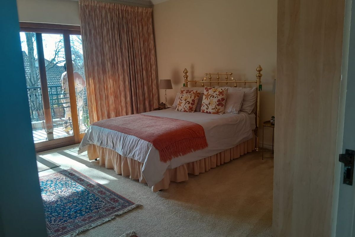 A carpeted bedroom featuring a built-in wardrobe, cornice detailing, and a sliding glass door providing direct access to an outdoor balcony.