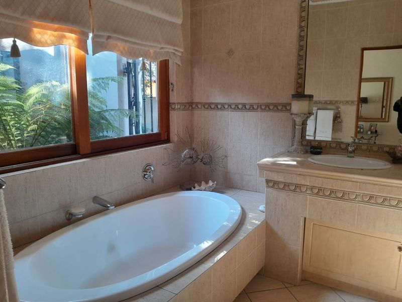 A functional bathroom featuring a built-in bathtub, a tiled vanity with an integrated basin, and a large wall-mounted mirror.