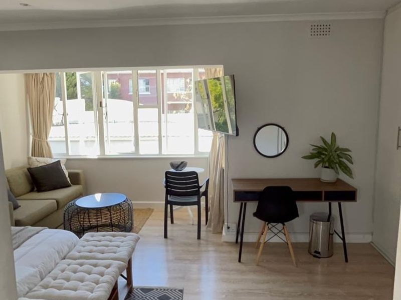 A bright and spacious bedroom featuring light-toned laminate flooring, recessed ceiling lighting, and a large window providing ample natural light.