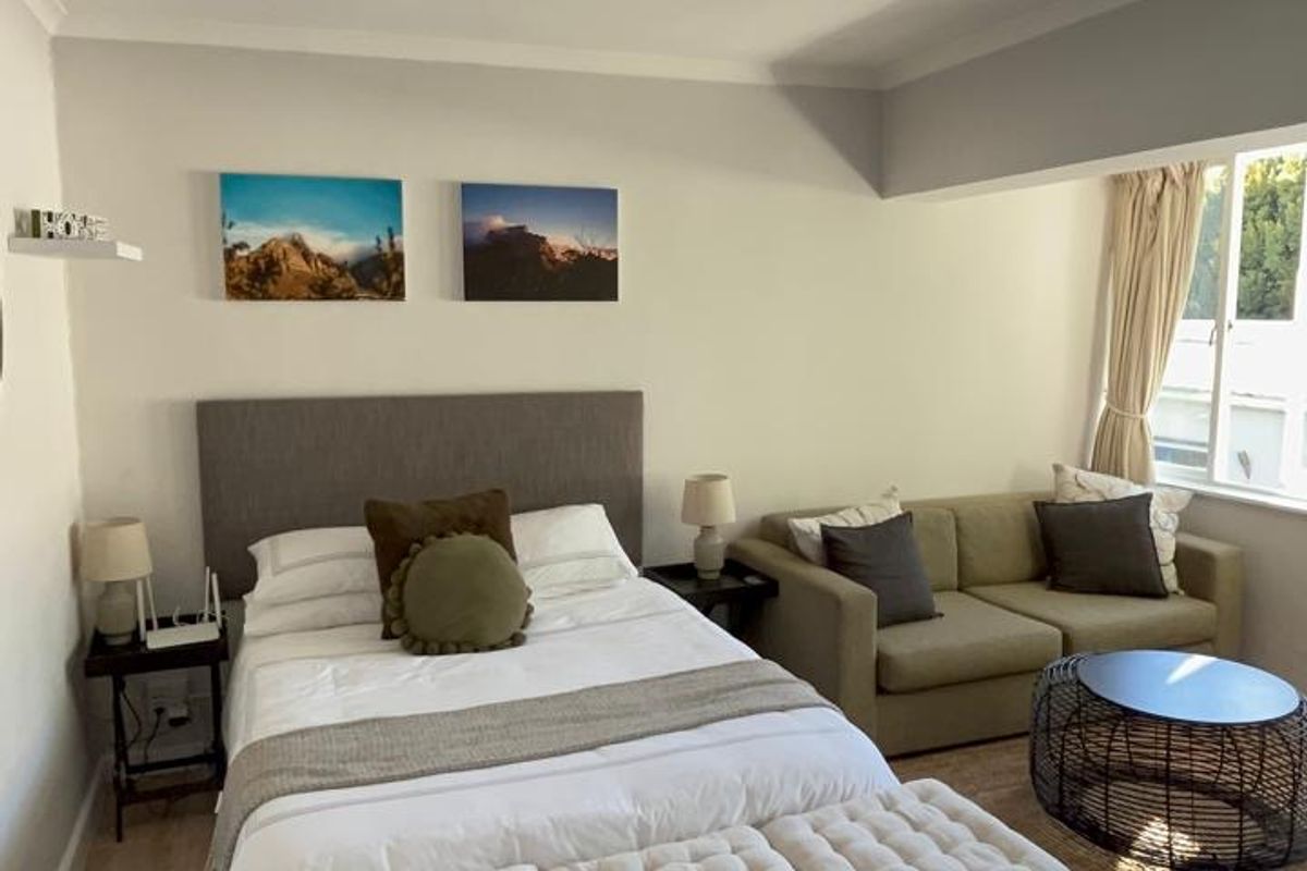 A well-lit bedroom featuring laminate flooring, recessed downlighting, and coving, offering a comfortable and functional living space.